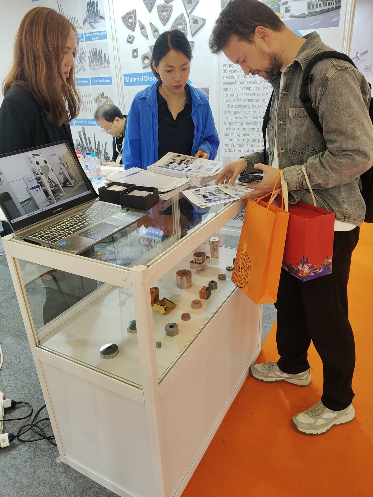 Exhibition visitors reviewing brochures beside a tooling display